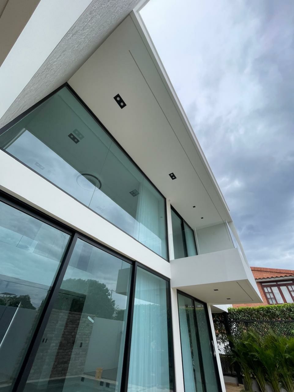 Fachada de casa con vidrio y voladizos blancos