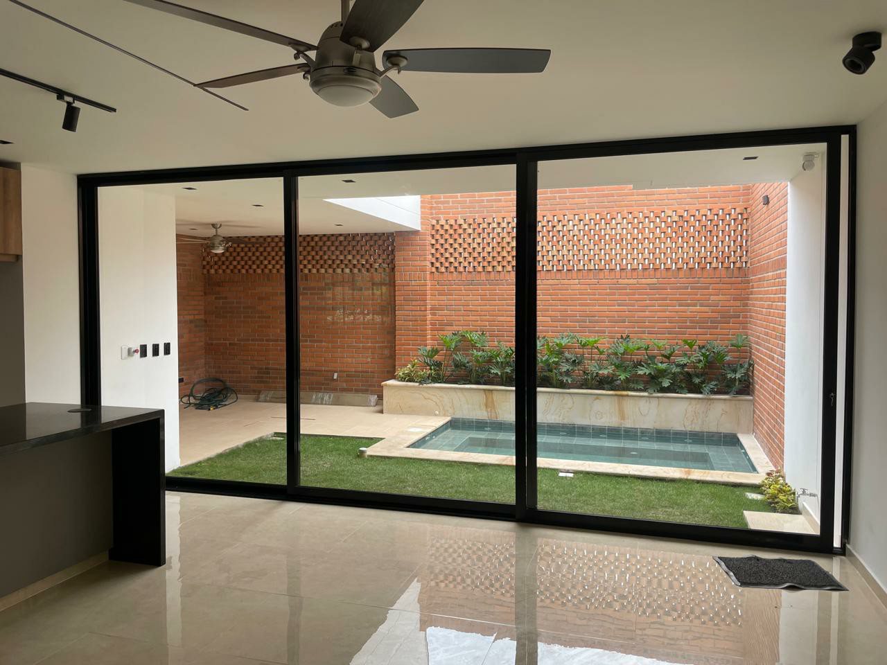 Puertas corredizas de vidrio y aluminio negro hacia un patio con piscina